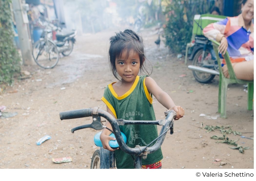 Petite fille cambodgienne tenant son vélo dans son village, bénéficiaire d’un programme d’éducation pour les filles